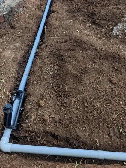 A healthy garden needs a reliable watering solution. This image shows the installation of a pop-up sprinkler head, part of a complete landscape irrigation system we design to ensure long-term plant health and easy maintenance.