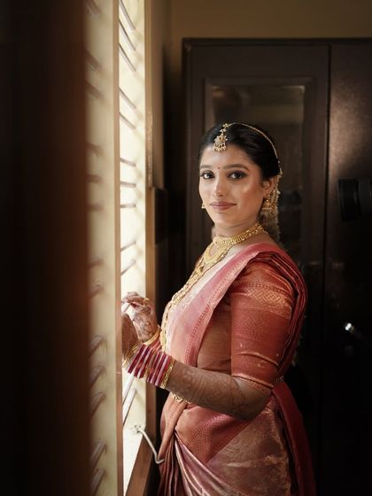 This bride looks so serene by the window. The natural light beautifully highlights the subtle, glowing makeup I created for her, which complements her traditional silk saree.