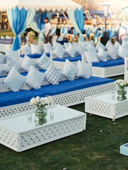 A relaxed, low-seating arrangement with white and blue decor, perfect for a daytime Mehendi, allowing guests to lounge comfortably.