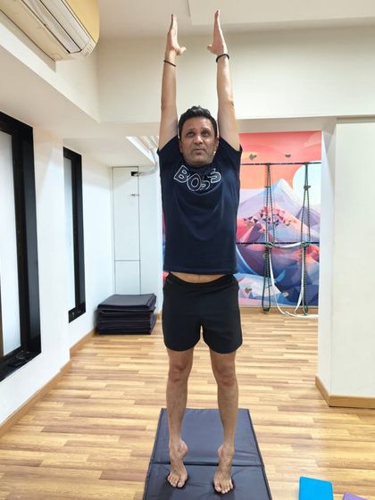 A male student demonstrates focus and control in this Tadasana variation. Yoga is a practice for every body, building strength and balance for men and women alike.