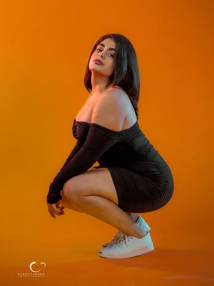 A low, athletic pose that combines strength and style. The orange background adds a burst of energy to this edgy and modern portrait.