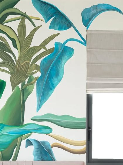 The mural's composition is carefully designed to interact with the room's features, like the window, creating a seamless blend of indoor art and outdoor views.