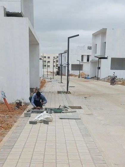 A craftsman carefully lays interlocking paver blocks for a new sidewalk. We oversee every detail of the construction phase to ensure the quality of execution matches the precision of our landscape architecture plans.
