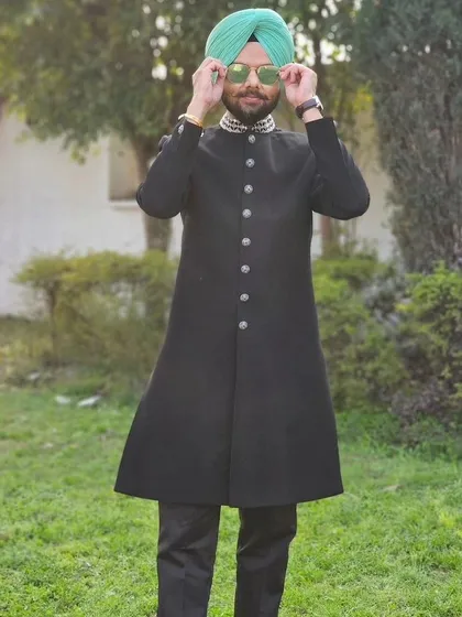 Jaspreet Singh adjusting his sunglasses while wearing our black Indo-western sherwani. A perfect example of how to add your own personality to our outfits.