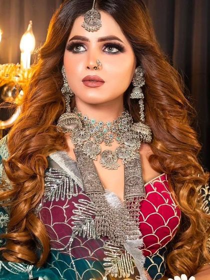 A model with long hair wearing a heavy, layered oxidised silver necklace set with matching jhumkas. This is a perfect statement piece for a sangeet or festival.