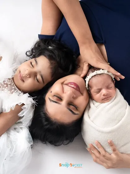 A creative overhead shot of a mother with her two daughters. This pose beautifully showcases the connection between a mom, her older child, and the new baby.