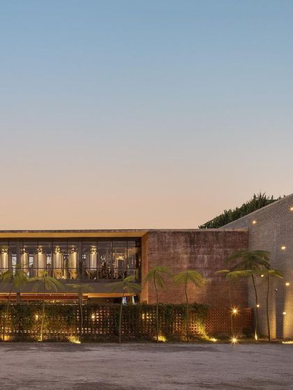 The exterior of Zero40 Brewery at sunset, showing the warm lighting on the brick facade and the surrounding landscape. The design creates a welcoming and atmospheric approach to the building.