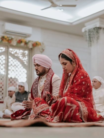 A low-angle shot of the couple during their Anand Karaj, creating a sense of reverence and focusing on their shared prayer.