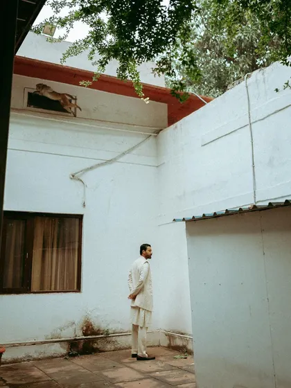 A wide architectural shot for Sanchit Sharma's campaign. The model is placed within a courtyard, using the environment to create a sense of scale and story.