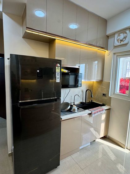 This side of the kitchen shows how we neatly integrate the refrigerator and microwave oven into the modular setup, maintaining a clean and uncluttered look.