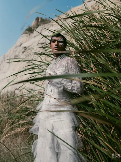 Another shot of the model amidst tall grass, creating a sense of being one with nature despite the high-fashion styling.