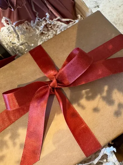 A simple, beautifully wrapped gift box tied with a red satin ribbon, ready to be included in a Valentine's Day surprise.