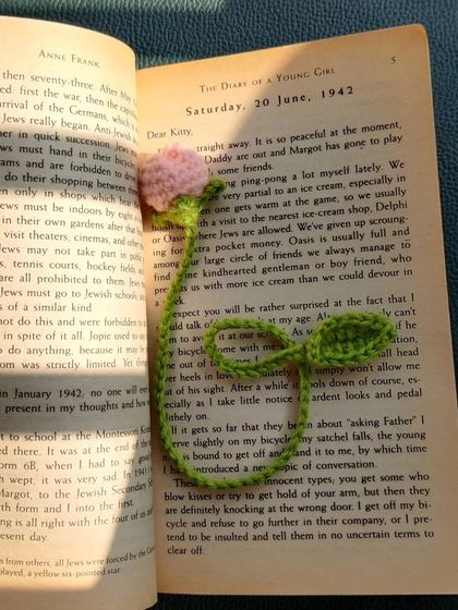 The pink tulip bookmark in a book, captured in bright sunlight.
