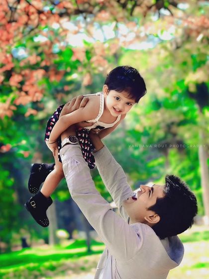 A heartwarming moment between a father and his child during an outdoor photoshoot. The genuine happiness on both their faces makes this a truly special memory of their bond.
