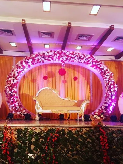 This full view of the circular stage design shows how it commands the space. The flanking floral arrangements and warm lighting complete this stunning setup for a memorable wedding or engagement.