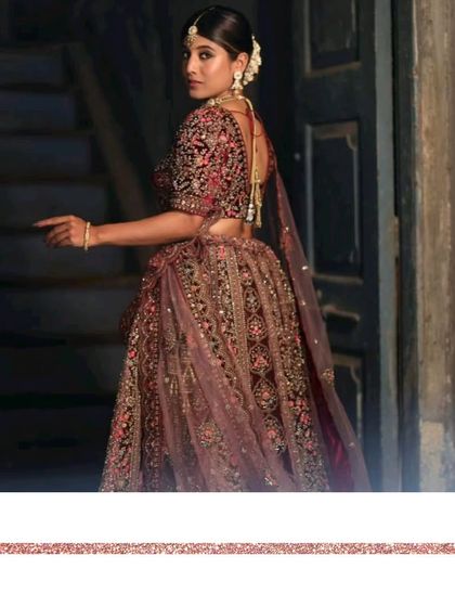 A side profile of our wine-colored velvet bridal lehenga, showing the intricate embroidery on the sleeves and the beautiful fall of the skirt.