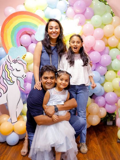 A happy family portrait surrounded by a rainbow of pastel balloons and unicorn cutouts. We create picture-perfect moments for you to cherish.