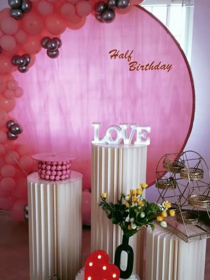 Celebrating the half-way mark to one! This sweet half-birthday decoration uses a pink backdrop and a matching balloon garland to create an adorable photo spot.