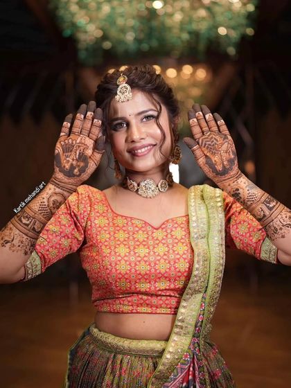A radiant bride with a big smile, showing her palms adorned with our beautiful mehandi.