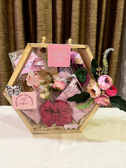 This pretty hexagonal acrylic basket hamper is perfect for her. It's filled with pink-themed items like scrunchies, face masks, and floral decorations, making it a gorgeous gift for a best friend or girlfriend.