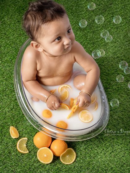 A candid shot of a baby in a milk bath, looking curiously at the bubbles floating by, adding a touch of magic to the scene.