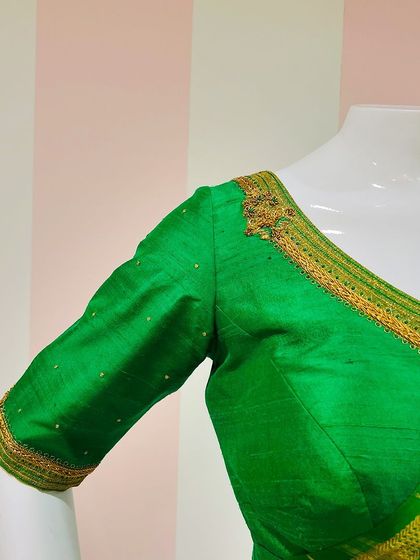 The front of the green raw silk blouse, featuring subtle embroidery along the neckline and sleeves.