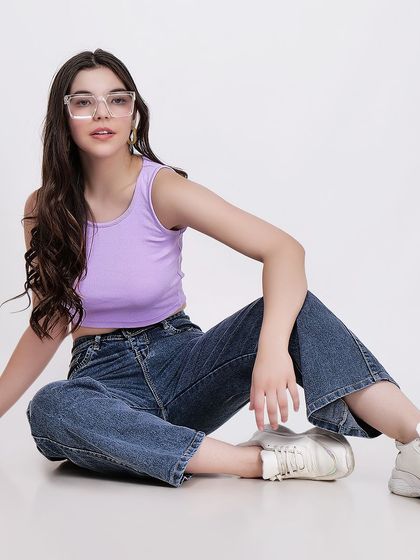 A classic seated pose that clearly shows the fit of both the tank top and the jeans, providing essential information for buyers.
