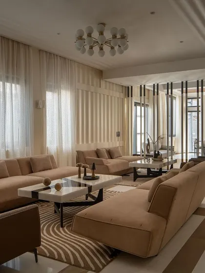 The living area is designed with a palpable synergy between architecture and interior design. Sleek furniture, soft upholstery, and a striking center table create a serene yet sophisticated ambiance.