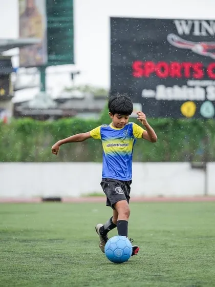 Just a kid, a ball, and a dream. A young player focused on his dribbling during a training session.