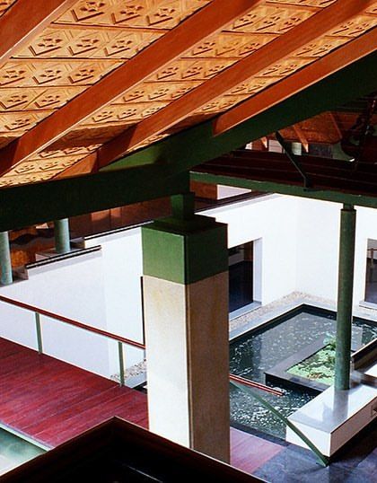 An interior view of the LMW office, showing the intricate patterned ceiling and green-painted structural columns. The design draws from traditional Indian architectural elements, reinterpreted in a contemporary language.