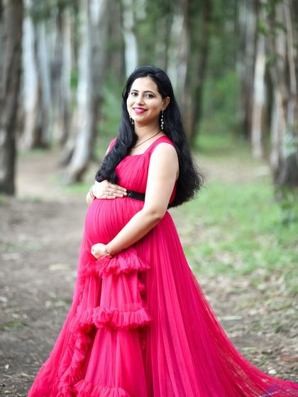 A beautiful portrait of a mom-to-be in a pink gown, posing in a forest setting.