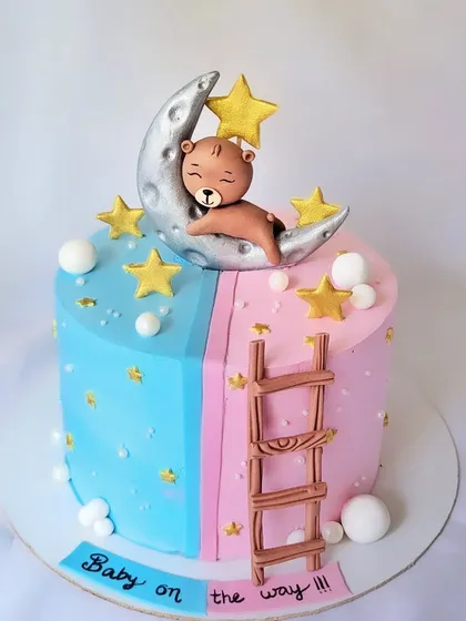 A "Baby on the way" cake in pink and blue. This design features a teddy bear sleeping on the moon, with a ladder connecting the two halves.