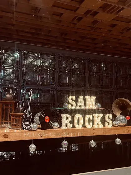 'SAM ROCKS' in marquee lights on the bar, surrounded by disco balls and vinyl records.