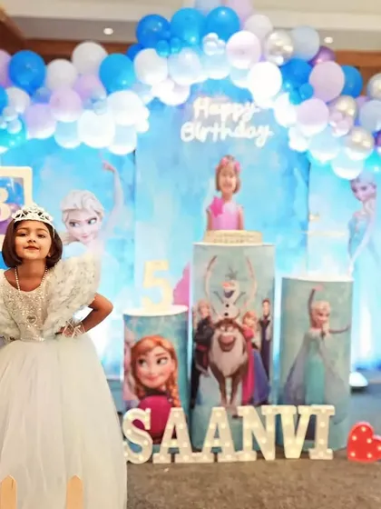 A full view of the Frozen-themed stage setup for Saanvi's birthday. The combination of balloon arches, character props, and custom lighting transforms the venue into the kingdom of Arendelle.