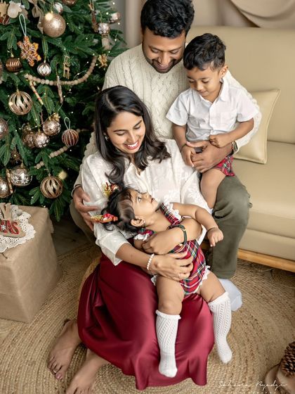 A candid moment from a Christmas family session. The parents are sharing a laugh while their children play, creating a natural and heartwarming memory of their time together.