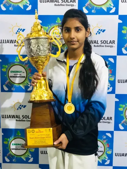Aarti Solanki, a gold medalist, proudly holding the team trophy. She is a powerful and skilled fighter.