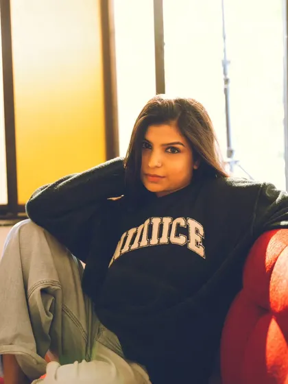 A casual and confident portrait on a red sofa, using the warm indoor light to create a cozy feel.