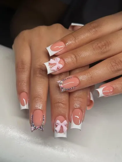 A modern French manicure with sculpted 3D bows and silver pixie dust accents. This shows how to add texture and sparkle to a classic look.