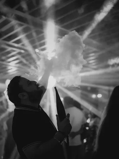 A dramatic shot of a guest at the after-party. The smoke and backlighting create a cool, atmospheric vibe in this black and white photo.