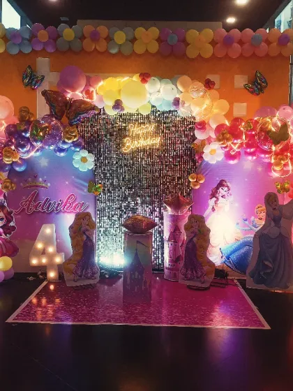 A magical Disney Princess theme featuring characters like Ariel and Elsa. The setup is lit with warm lights against a shimmer backdrop, creating an enchanting scene for a 4th birthday.