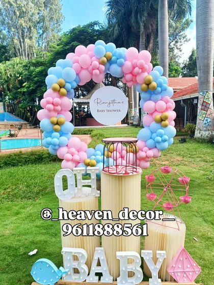This outdoor baby shower decor features a circular balloon arch in pink and blue, ideal for a gender reveal party. We added light-up letters and other fun props to complete the festive look by the poolside.