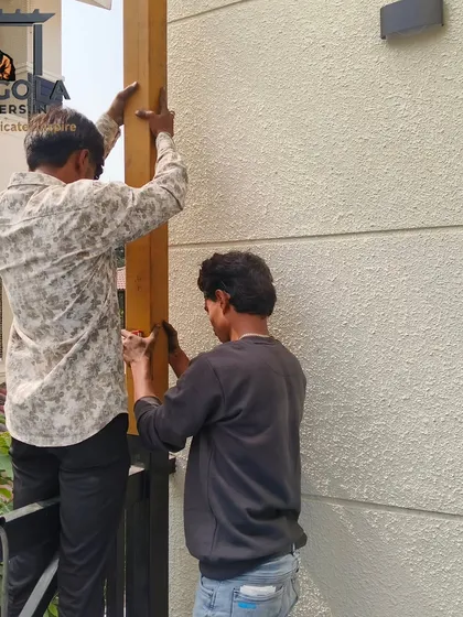Two team members work together to install a vertical support post for a pergola. This image demonstrates the teamwork and care taken during the on-site assembly to ensure the structure is secure and perfectly aligned.
