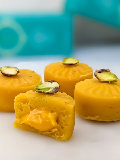 Our Mango Cake Mithai, featuring a rich mango-flavored filling and garnished with a pistachio slice. It's a taste of summer in a bite-sized treat.