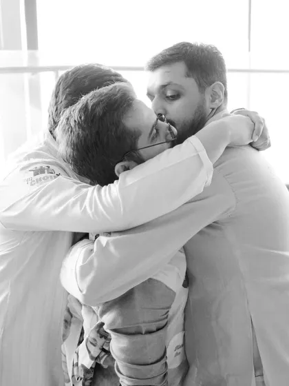 A heartwarming black and white photo of the groom sharing a group hug with his groomsmen, a testament to their strong bond.