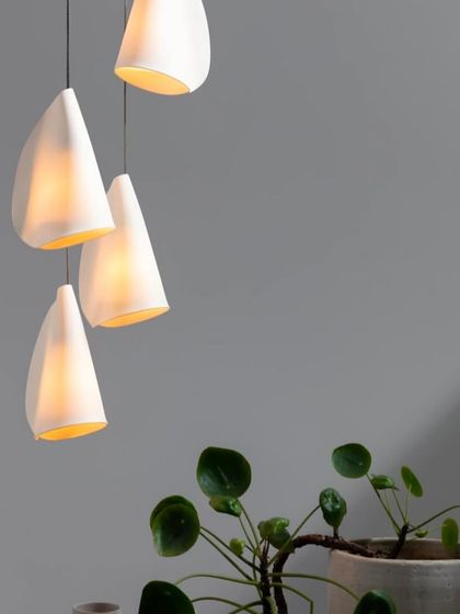 A small cluster of Bocci 21 pendants provides soft, ambient light next to a houseplant, highlighting the series' organic and natural feel.