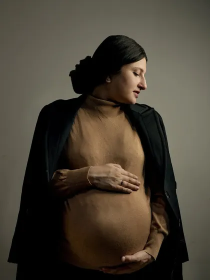 A classic and elegant maternity portrait. The simple, focused lighting highlights the beautiful silhouette of the baby bump, creating a timeless piece of art that you will cherish forever.