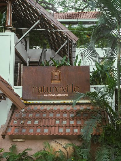 The beautiful sign for our Natureville Holistic Wellness Center, nestled among the trees. This image captures the essence of our space, a sanctuary in the city where you can reconnect with nature and yourself.