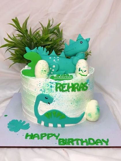 A front view of the dino-themed cake, showing the cute brontosaurus and other details.