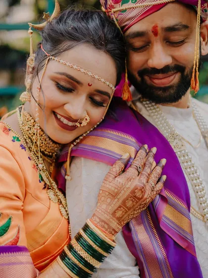 An emotional and tender moment captured beautifully. The bride rests her head on the groom's shoulder, her detailed henna and green bangles adding to the richness of the image.