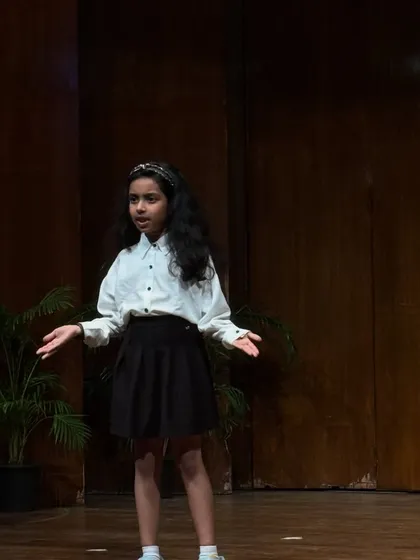 A student gestures expressively while delivering her lines, demonstrating strong non-verbal communication skills.